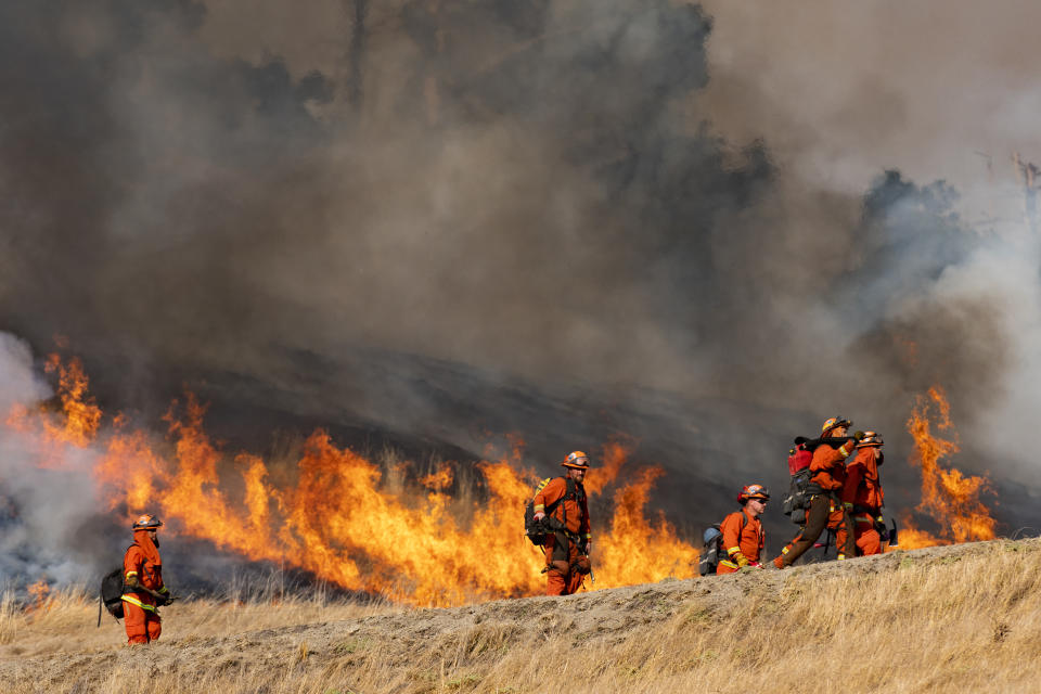 Fire fighters walk by a back fire they set in an effort to control the wildfire in Geyserville, California on October 26, 2019. 190,000 people are ordered to evacuate from Healdsburg, Windsor, Guerneville, Forestville, Occidental and several other communities as Kincade Fire grows to over 25,000 acres. (Photo by Yichuan Cao/NurPhoto via Getty Images)