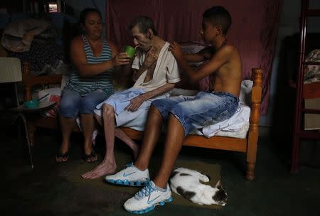 Cerebrovascular accident (CVA) patient Pedro, drinks water with the help of his daughter Daniela (L), 38, inside their house in Brasilandia slum, of which they are without water for 13 hours a day, in Sao Paulo February 11, 2015. REUTERS/Nacho Doce