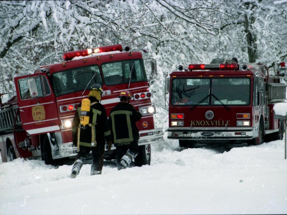 Knoxville fire fighters return to their fire truck, which has slid off the street, when responding to a call of a chimney fire on Carlton St. on March 13, 1993.