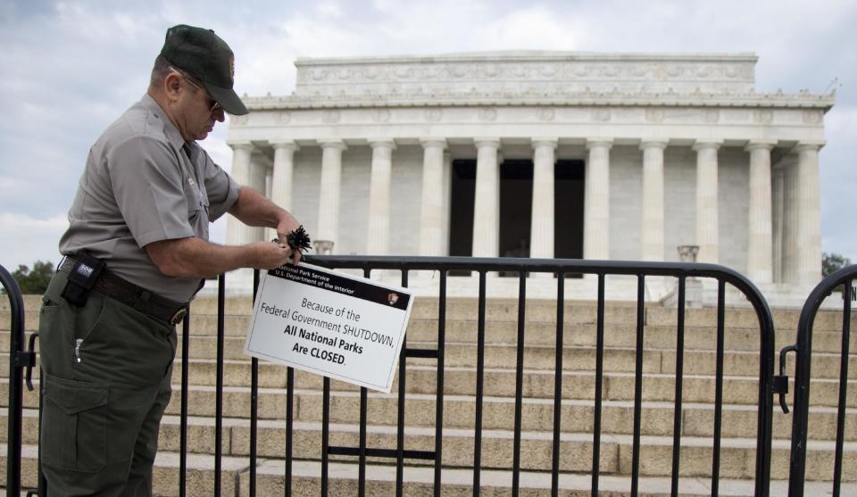 A National Park Service employee posts a sign on a barricade to close access to the Lincoln Memorial in Washington, Tuesday, Oct. 1, 2013. Congress plunged the nation into a partial government shutdown Tuesday as a long-running dispute over President Barack Obama's health care law stalled a temporary funding bill, forcing about 800, 000 federal workers off the job and suspending most non-essential federal programs and services. (AP Photo/Carolyn Kaster)