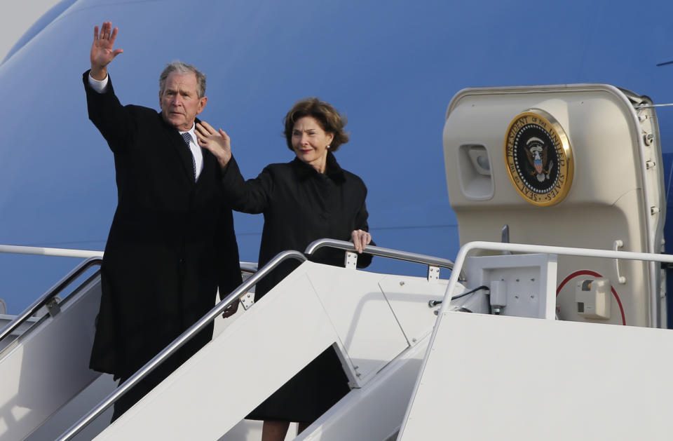 Former President George W. Bush waves to the crowd along with his wife, Laura Bush, after the flag-draped casket of former President George H.W. Bush was carried by a joint services military honor guard to an Air Force jet during a departure ceremony at Andrews Air Force Base, Md., Wednesday, Nov. 5, 2018. (AP Photo/Steve Helber)