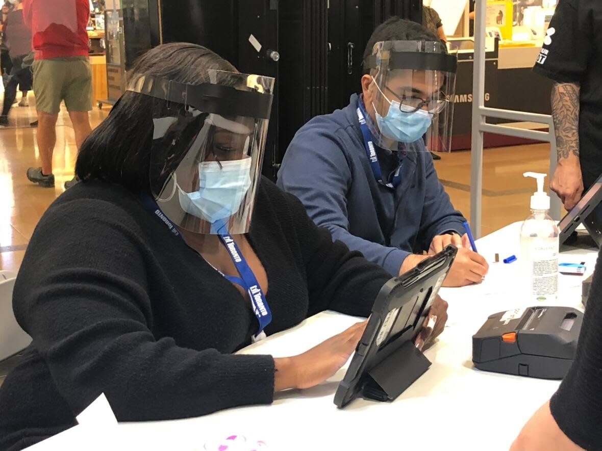 Health care workers make notes at a COVID-19 vaccination clinic in Sherway Gardens shopping mall on Sept. 26, 2021 as part of Toronto's #ShopAndVax campaign. (Robert Krbavac/CBC - image credit)