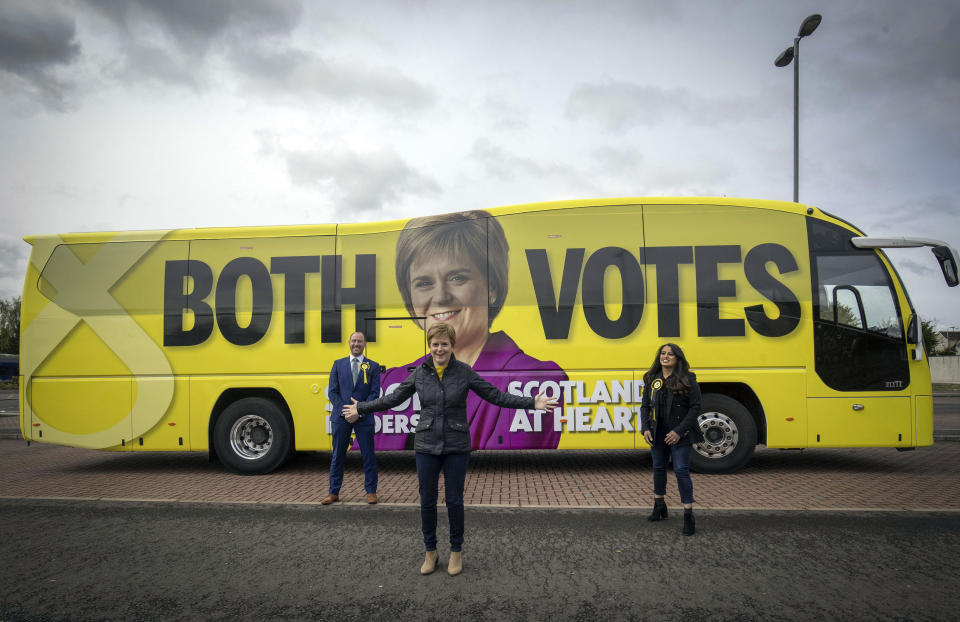 First Minister of Scotland and leader of the SNP Nicola Sturgeon, with party candidates Neil Gray, left, and Anum Qaisar-Javed, right, alongside the party's campaign bus during campaigning for the Scottish Parliamentary election, in Airdrie, Scotland, Tuesday, May 4, 2021. Scotland holds an election Thursday that could hasten the breakup of the United Kingdom. The pro-independence Scottish National Party is leading in the polls and a big victory will give it the the moral right and the political momentum to hold a referendum on whether Scotland should end its three-century union with England. First Minister Nicola Sturgeon has downplayed independence in her campaign, stressing her credentials as a safe pair of hands to lead Scotland’s recovery from the pandemic. (Jane Barlow/PA via AP)