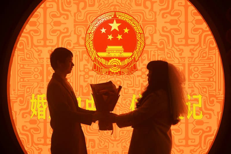FILE PHOTO: Couple pose for pictures on Valentine's Day at a marriage registration office in Hangzhou