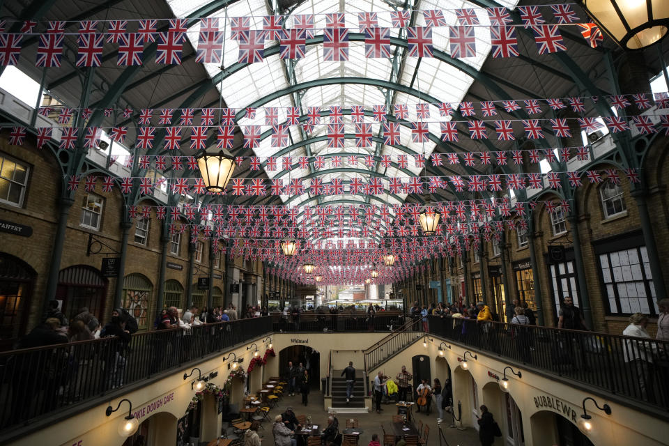 FILE - Union flags are displayed above the south hall of the Covent Garden district of London, to mark the upcoming Platinum Jubilee of the 70 year reign of Britain's Queen Elizabeth II, Friday, May 20, 2022. Britain is getting ready for a party featuring mounted troops, solemn prayers — and a pack of dancing mechanical corgis. The nation will celebrate Queen Elizabeth II’s 70 years on the throne this week with four days of pomp and pageantry in central London. (AP Photo/Matt Dunham, File)