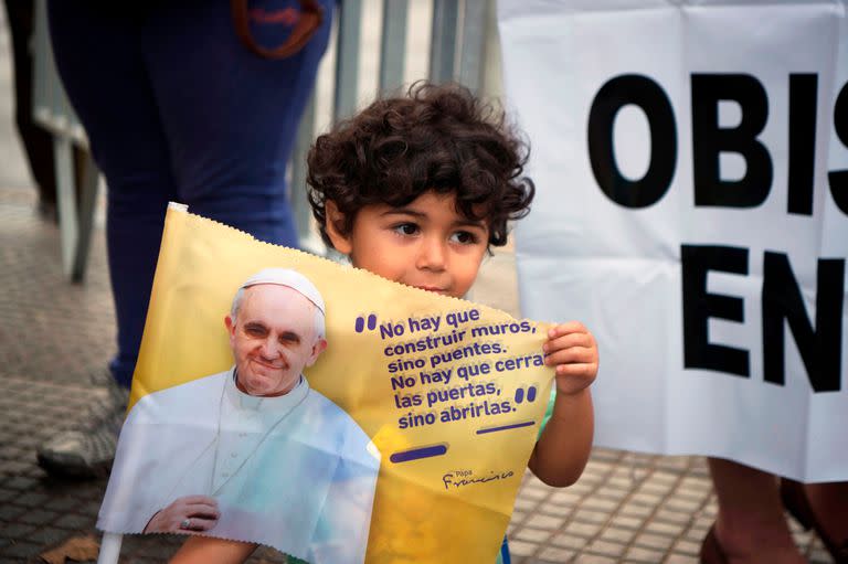 Un niños sostiene un cartel mientras espera ver al Papa que recorre las calles de Santiago