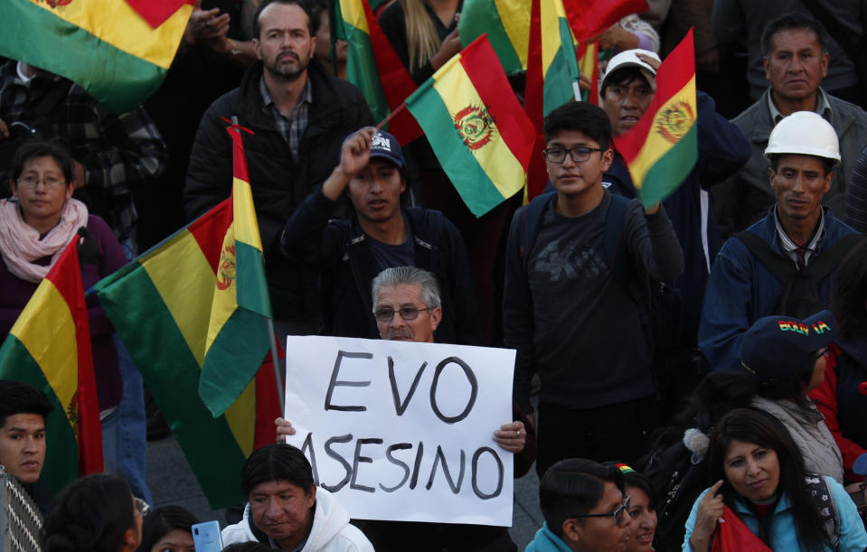 An anti-government protester holds a sign with a message that reads in Spanish message: "Evo killer" as people gather against the reelection of President Evo Morales, in La Paz, Bolivia, Thursday, Oct. 31, 2019. Violence has escalated since Morales was declared the winner of the Oct. 20 vote amid delays in the vote count. The opposition alleges the outcome was rigged to give Morales enough of a majority to avoid a runoff election; the president denies any irregularities. (AP Photo/Juan Karita)