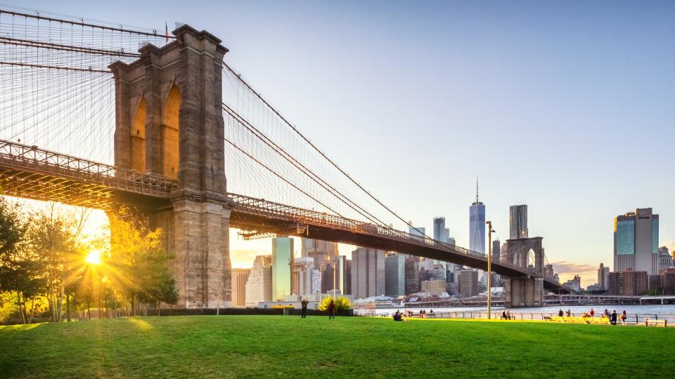 View of Brooklyn Bridge and Lower Manhattan at sunset with sun Flare and a blank space.