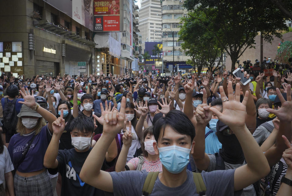 FILE - In this Wednesday, July. 1, 2020 file photo, protesters against the new national security law gesture with five fingers, signifying the "Five demands - not one less" on the anniversary of Hong Kong's handover to China from Britain in Hong Kong. Britain’s government has announced that it will open a new special pathway to obtaining U.K. citizenship for eligible Hong Kongers from January 2021. The Home Office said Wednesday, July 22, 2020, that holders of the British National Overseas passport and their immediate family members can move to the U.K. to work and study. The change to immigration rules was introduced after China imposed a new, sweeping national security law on Hong Kong. Those eligible can access the British job market at any skill level and without a salary threshold, but won't have access to public funds. (AP Photo/Vincent Yu, file)