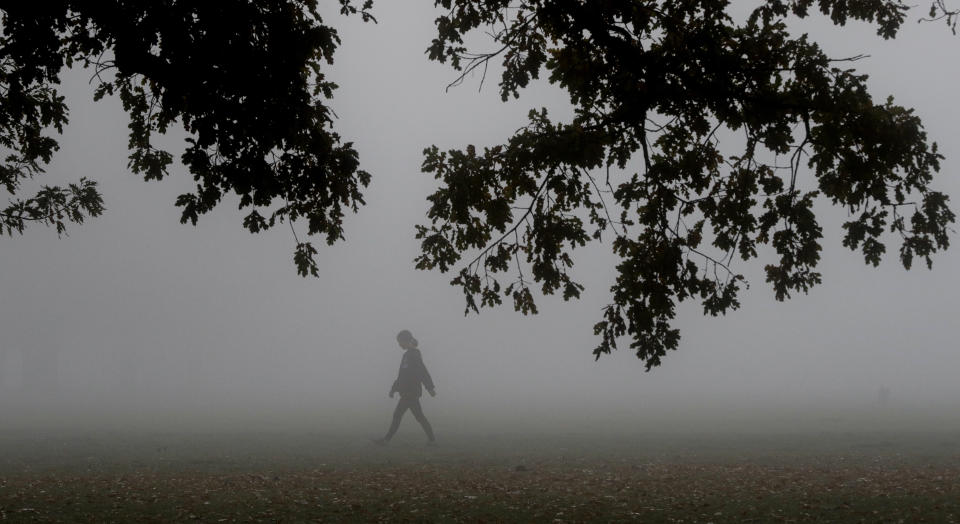 A woman exercises in Hagley Park as fog envelopes Christchurch, New Zealand, Thursday, April 23, 2020. (AP Photo/Mark Baker)