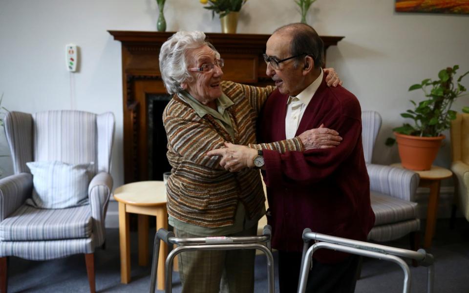 Residents Susan Crowe, 96, and Antonio Hernandez, 82, hug each other at Alexander House Care Home in Wimbledon - HANNAH MCKAY/REUTERS
