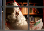 FILE PHOTO: A man dressed as Santa Claus reads letters from children from around the world in his office at the Santa Claus' Village at the Arctic Circle near Rovaniemi, Finland December 18, 2007. REUTERS/Kacper Pempel/File Photo