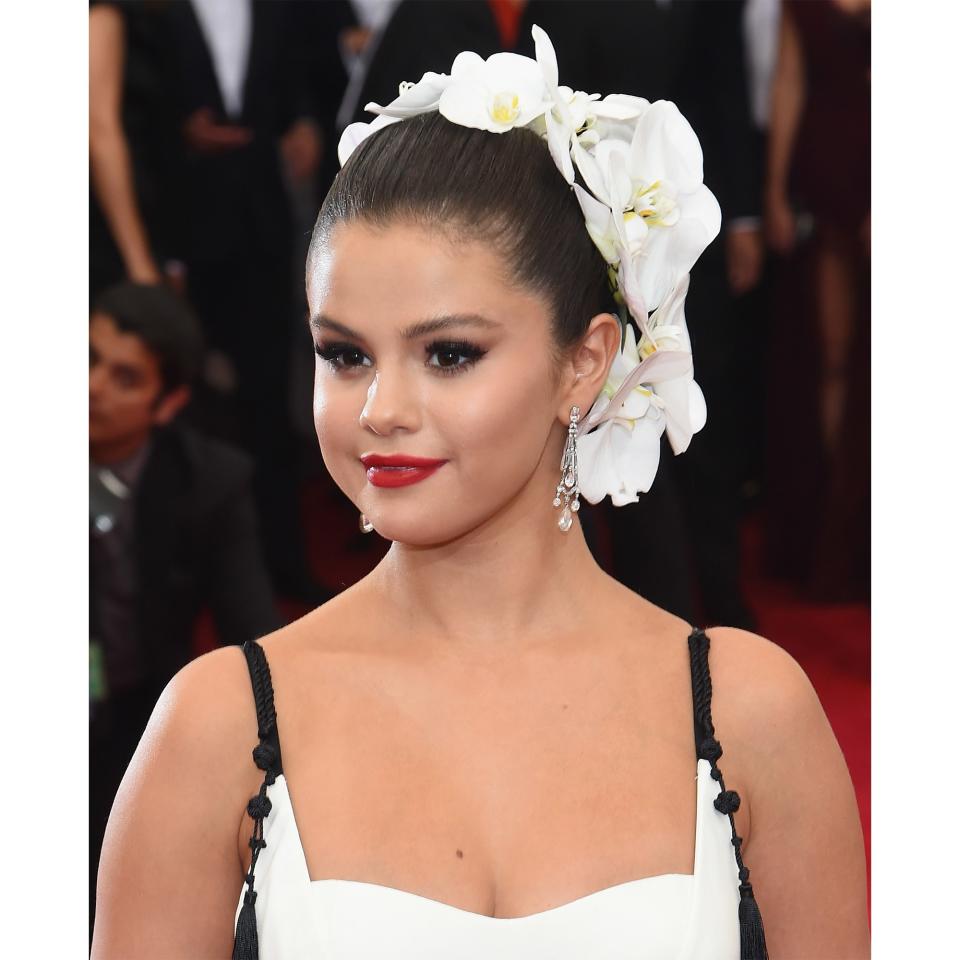 <p>For the Met Gala in 2015 — the theme was "China: Through the Looking Glass" — Gomez slicked her hair into a tight bun, letting a headful of white silk flowers do all the talking instead.</p>