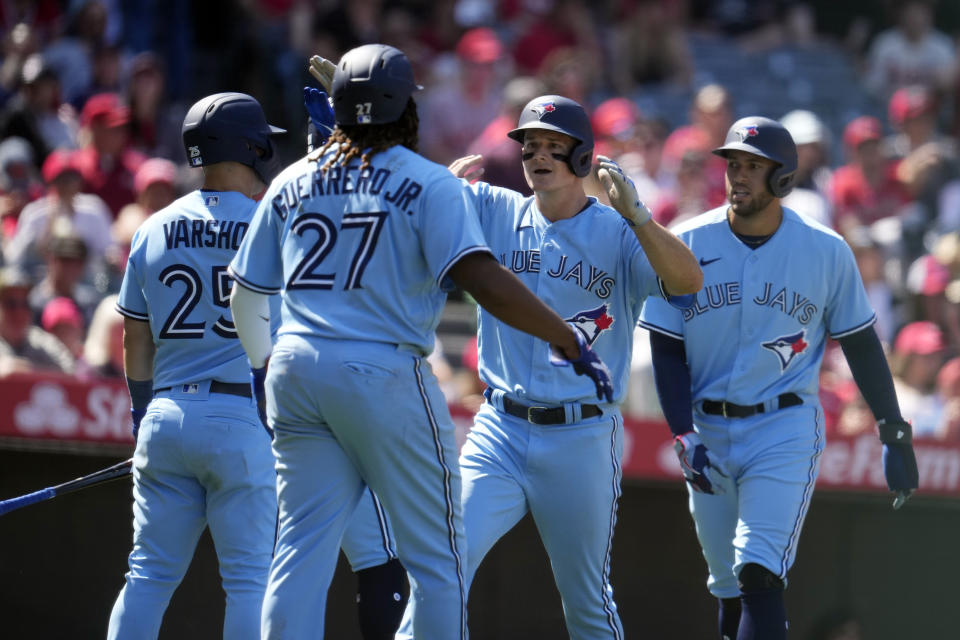 Toronto Blue Jays' Matt Chapman, second from right, is met at home plate by George Springer, right, Vladimir Guerrero Jr. (27) and Daulton Varsho (25) after Chapman's grand-slam during the sixth inning of a baseball game against the Los Angeles Angels Sunday, April 9, 2023, in Anaheim, Calif. (AP Photo/Marcio Jose Sanchez)
