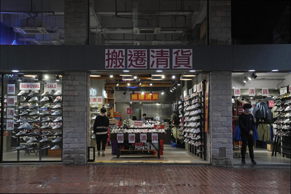 Shopkeepers promote a "moving out" clearance sale at a store in Hong Kong, Thursday, Feb. 17, 2022. Hong Kong on Thursday reported 6,116 new coronavirus infections, as the city’s hospitals reached 90% capacity and quarantine facilities are at their limit, authorities said. (AP Photo/Kin Cheung)