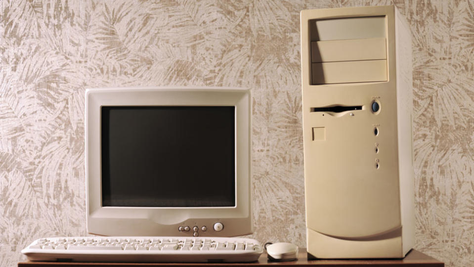 Computer with keyboard and mouse by CPU on wooden table against wall