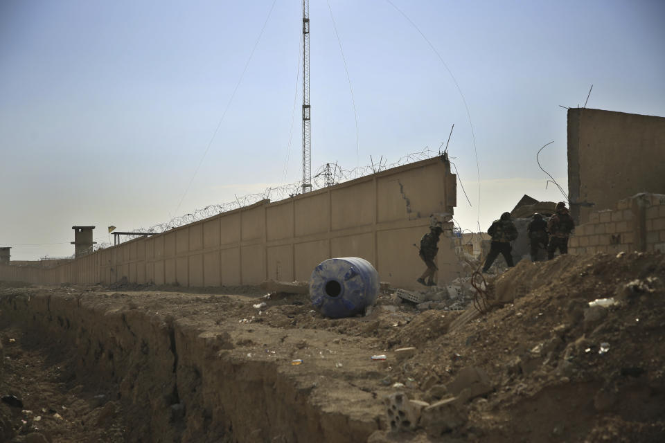 Kurdish-led Syrian Democratic Forces fighters, take their positions at the defense wall of Gweiran Prison, in Hassakeh, northeast Syria, Sunday, Jan. 23, 2022. Clashes between U.S.-backed Syrian Kurdish fighters and militants continued for a fourth day Sunday near a prison in northeastern Syria that houses thousands of members of the Islamic State group, the Kurdish force said. (AP Photo/Hogir Al Abdo)