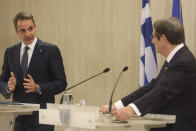 This image provided from Cyprus' press and information office, Greece's Prime minister Kyriakos Mitsotakis, left, talks as he looks the Cyprus President Nicos Anastasiades during a press conference after their talks at the presidential palace in capital Nicosia, Cyprus, on Monday, Feb. 8, 2021. Mitsotakis is in Cyprus for one-day official visit. (Stavros Ioannides, PIO via AP)