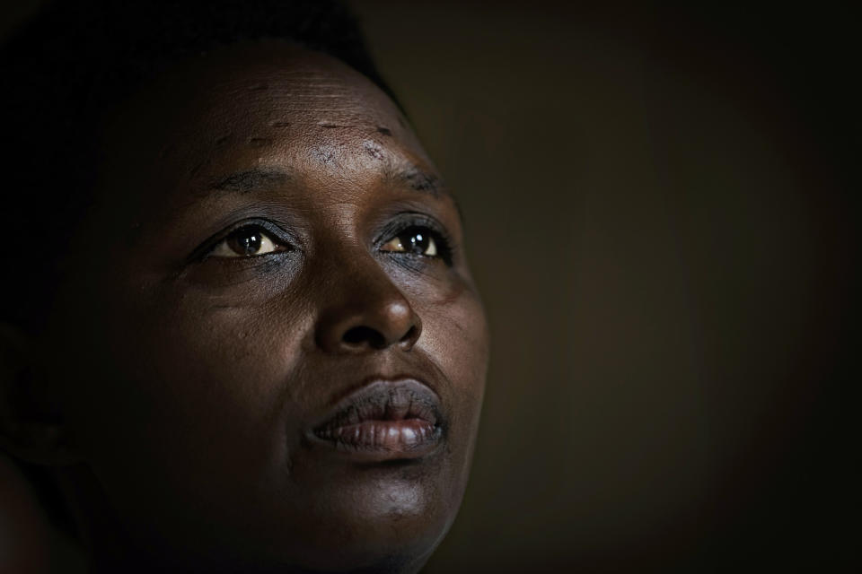 In this photo taken Thursday, April 4, 2019, genocide survivor Jannette Mukabyagaju, 42, recounts her experience in her home in the reconciliation village of Mbyo, near Nyamata, in Rwanda. Twenty-five years after the genocide the country has six "reconciliation villages" where convicted perpetrators who have been released from prison after publicly apologizing for their crimes live side by side with genocide survivors who have professed forgiveness. (AP Photo/Ben Curtis)