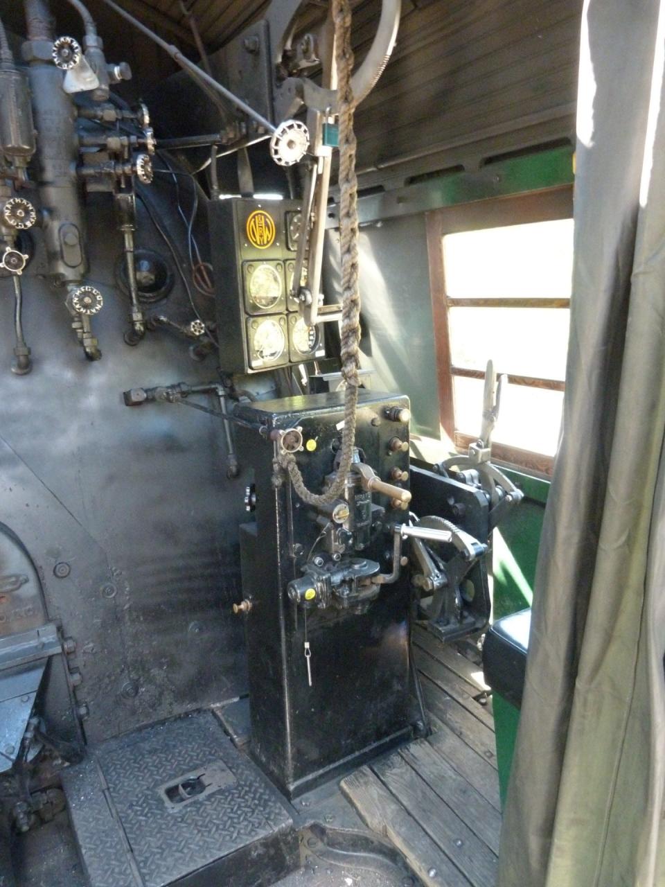 Inside the cab of the gigantic locomotive, the engineer sits on the right and uses the throttle (brass colored) to propel the train. The braided rope triggers the whistle which produces the lonesome moan that evokes many memories.