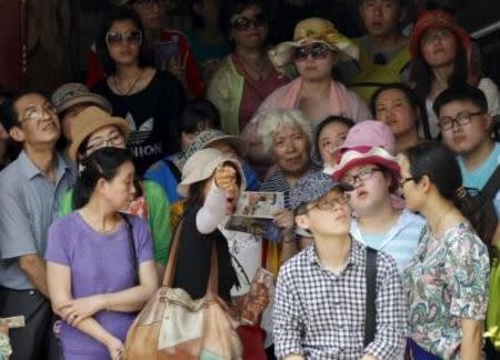 Chinese tourists listen to their guide as they visit at Wat Phra Kaeo (Emerald Buddha Temple) in Bangkok March 23, 2015. P REUTERS/Chaiwat Subprasom