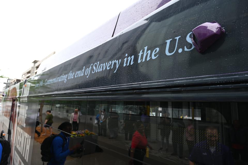 Members of the public and Dwana Bradley, general chairperson of nonprofit organization Iowa Juneteenth, unveil the Juneteenth-themed DART bus that will be in operation during the month of June.