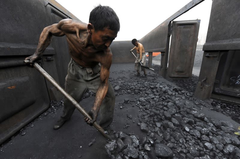 FILE PHOTO: Workers unload coal at a storage site along a railway station in Hefei,