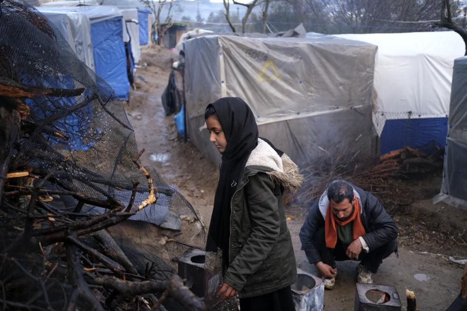 Migrants use wood to make a fire, outside the perimeter of the overcrowded Moria refugee camp after a rainfall on the northeastern Aegean island of Lesbos, Greece, on Tuesday, Jan. 28, 2020. Greece has been the first point of entry into the European Union for hundreds of thousands of people fleeing war or poverty at home, with most arriving on eastern Aegean islands from nearby Turkey. (AP Photo/Aggelos Barai)