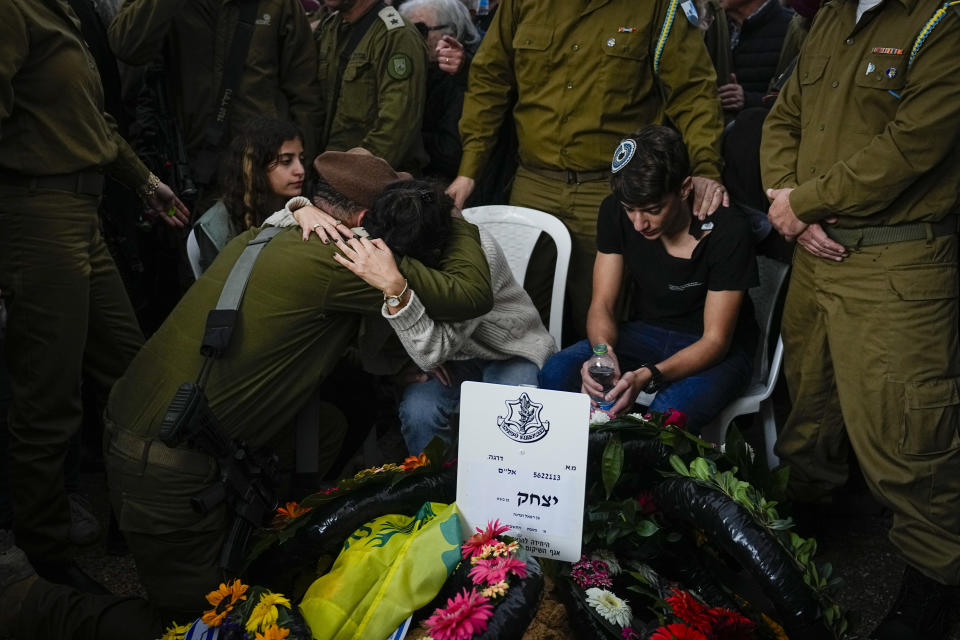 An Israeli soldier consoles Adar Ben Basat, during the funeral of her husband Col. Itzhak Ben Basat, in Kfar Tavor, Israel, Wednesday, Dec. 13, 2023. Ben Basat, 44, was killed during the Israeli military's ground operation in the Gaza Strip. while the army is battling Palestinian militants in the war ignited by Hamas' Oct. 7 attack into Israel. (AP Photo/Ariel Schalit)