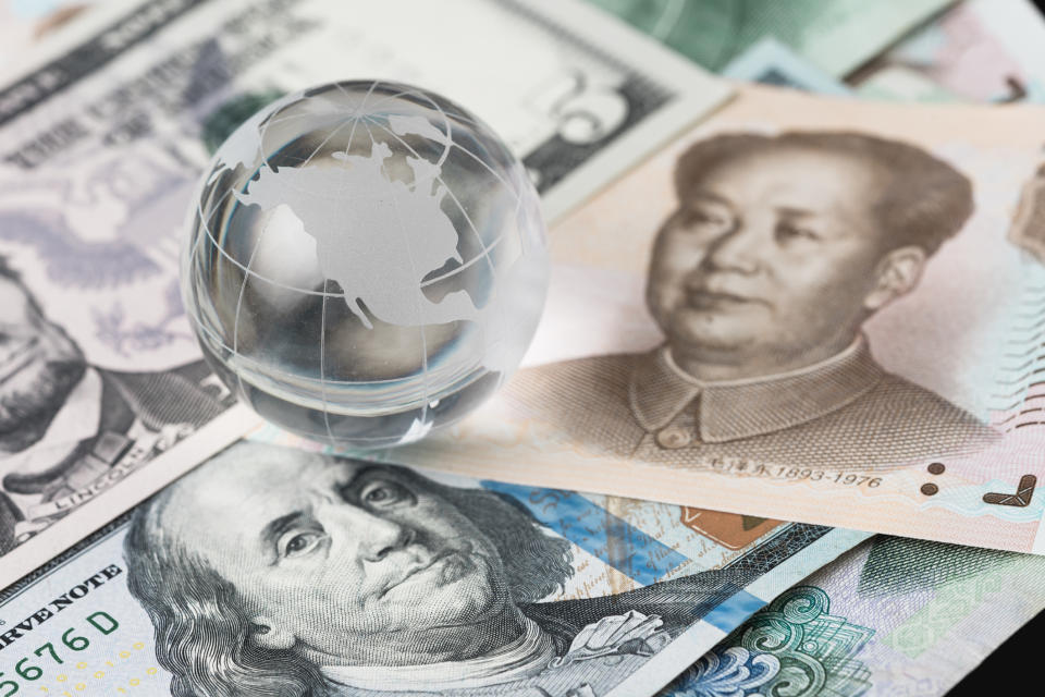 American and Chinese bills spread across a table with a glass sculpture of a globe