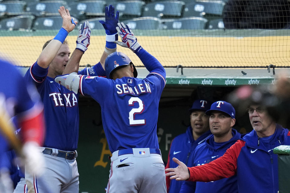Texas Rangers' Marcus Semien, center, celebrates with teammates at the dugout after hitting a solo home run against the Oakland Athletics during the sixth inning of a baseball game in Oakland, Calif., Thursday, May 11, 2023. (AP Photo/Godofredo A. Vásquez)