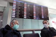 FILE PHOTO: Travellers wearing protective face masks wait for their flights at Nice International airport in Nice