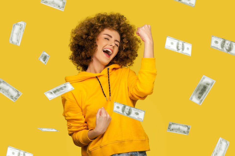 A person celebrates while being showered with cash.