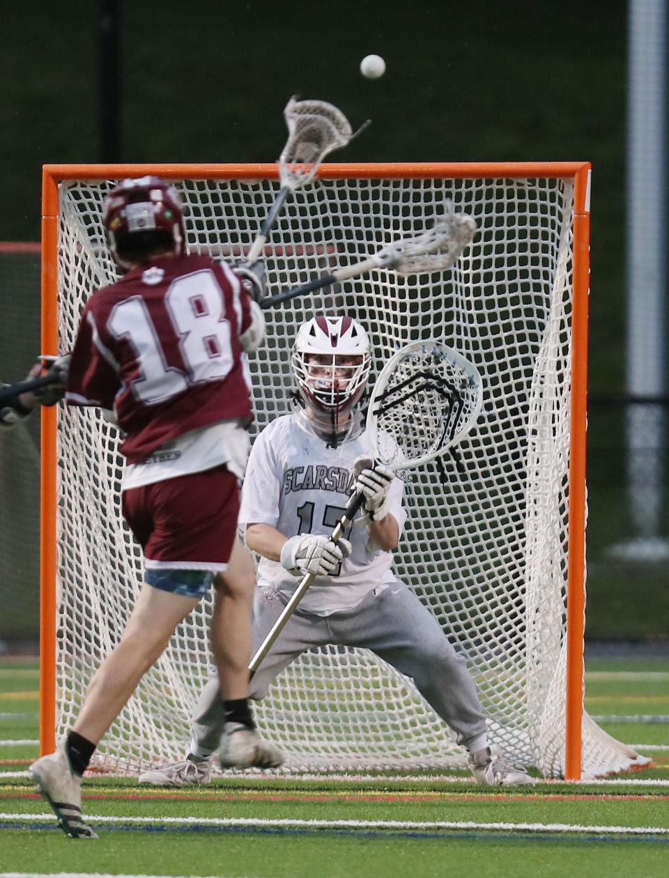 Kingston's Cody Baker (18) fires a shot on Scarsdale goalie Andrew Lehrman (17) during a boys lacrosse sub-regional playoff game at Mamaroneck High School on June 1.