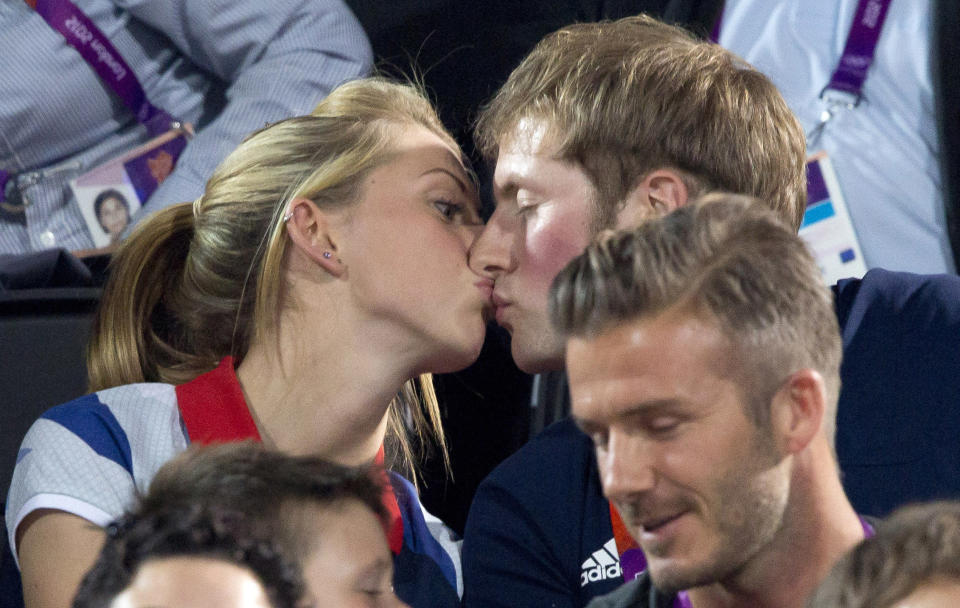 Gold medal-winning British cyclists Laura Trott and Jason Kenny kiss whilst sitting in front of footballer David Beckham during the women's beach volleyball final at Horse Guards Parade during the London 2012 Olympic Games August 8, 2012. REUTERS/Neil Hall (BRITAIN - Tags: SPORT OLYMPICS TPX IMAGES OF THE DAY CYCLING VOLLEYBALL)