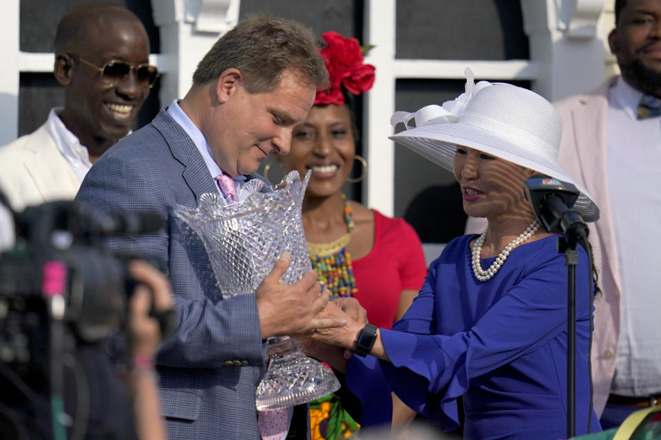 Maryland first lady Yumi Hoagan, right, hands a trophy to trainer Michael Trainer Michael J. Maker after his horse, Army Wife, won the Black-Eyed Susan Stakes horse race at Pimlico Race Course, Friday, May 14, 2021, in Baltimore. (AP Photo/Julio Cortez)