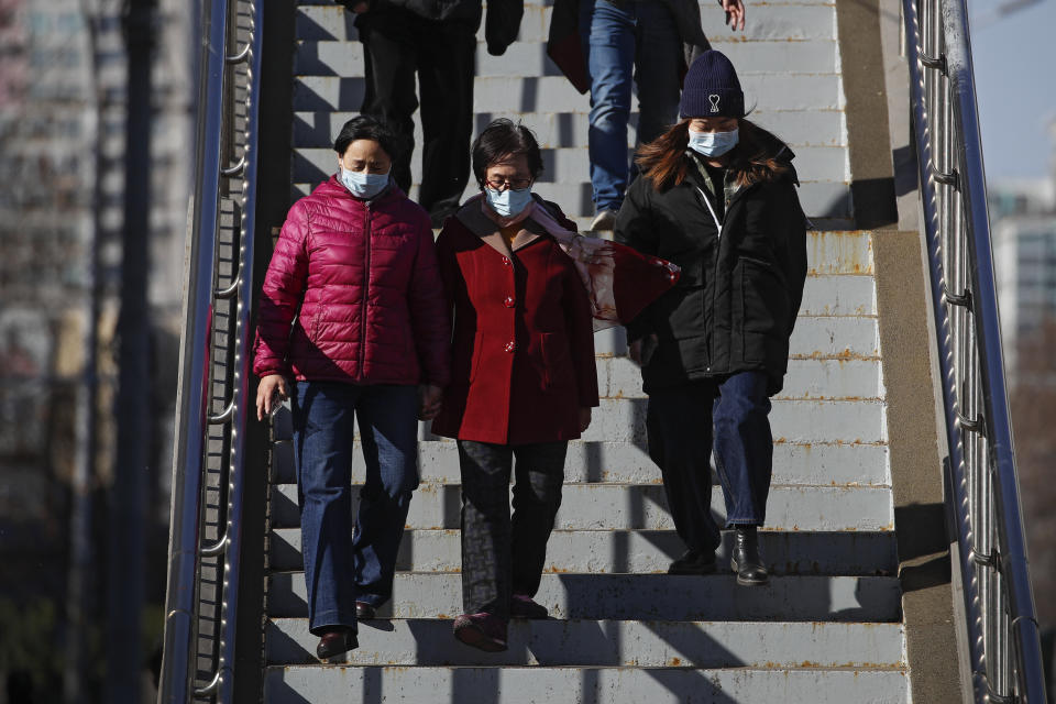 People wearing face masks to help curb the spread of the coronavirus walk down a pedestrian overhead bridge in Beijing, Sunday, March 21, 2021. (AP Photo/Andy Wong)