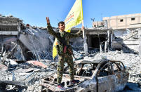 <p>A member of the Syrian Democratic Forces (SDF), which is backed by U.S. Special Forces troops, holds up the SDF flag at the Al-Naim square in Raqqa on Oct. 17, 2017. (Photo: Bulent Kilic/AFP/Getty Images) </p>