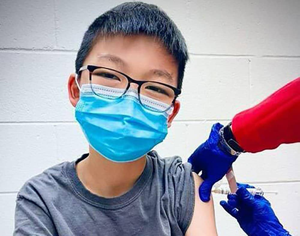 In this Dec. 22, 2020, photo, provided by Richard Chung, his son Caleb Chung receives the first dose of Pfizer coronavirus vaccine or placebo as a trial participant for kids ages 12-15, at Duke University Health System in Durham, N.C. (Richard Chung via AP)