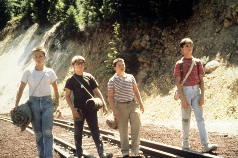 Four boys from the film "Stand by Me" walking on railroad tracks in casual attire