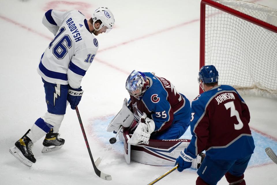 Colorado Avalanche goaltender Darcy Kuemper, center, stops a shot by Tampa Bay Lightning right wing Taylor Raddysh as as Avalanche's Jack Johnsonin watches during the third period of an NHL hockey game Thursday, Feb. 10, 2022, in Denver. The Avalanche won 3-2. (AP Photo/David Zalubowski)