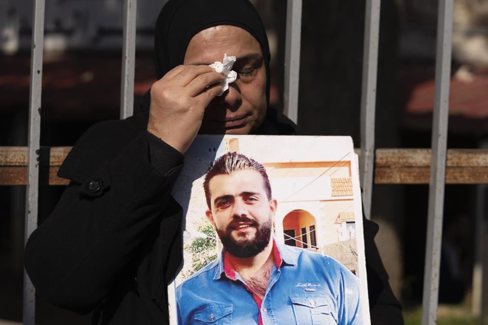 A relative of victims of the deadly 2020 Beirut port explosion cries as holds a portrait of her son during a protest in front of the Justice Palace, in Beirut, Lebanon, Thursday, Jan. 26, 2023. Scores of protesters Thursday scuffled with riot police as they tried to break into the Beirut Justice Palace, rejecting an order from Lebanon's judiciary that further crippled the probe into a massive port explosion over two years ago. (AP Photo/Hassan Ammar)