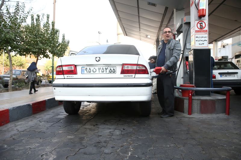 FILE PHOTO: A man fills up his car's tank at a petrol station, after fuel price increased in Tehran