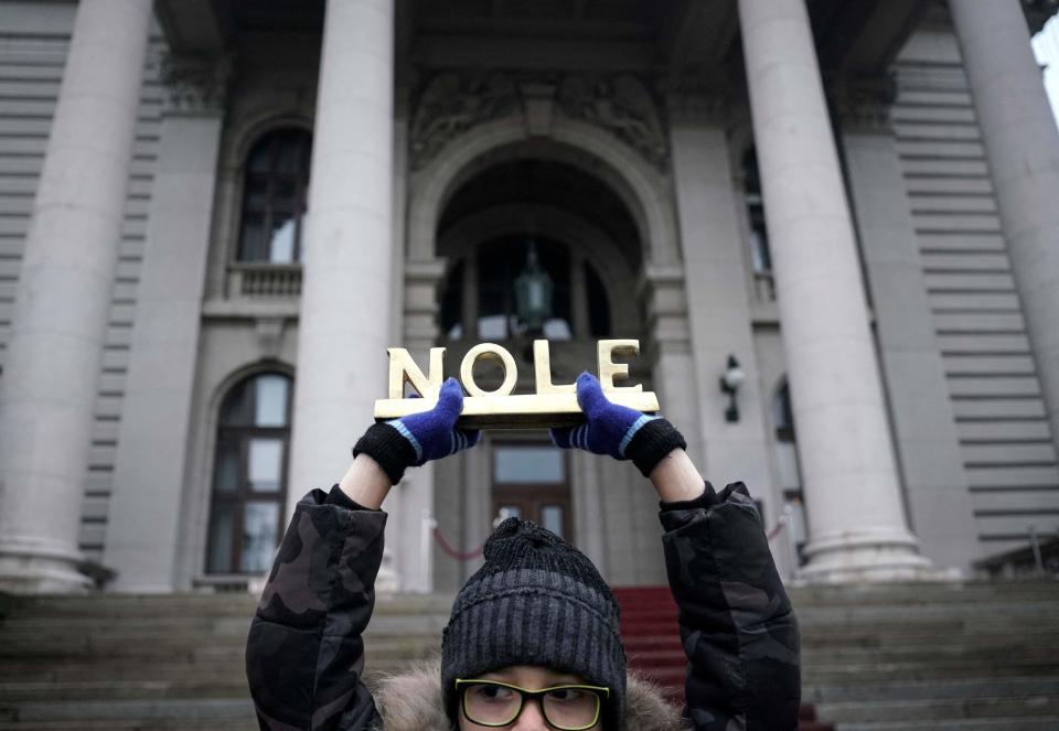 A protestor holds a sign that reads, 