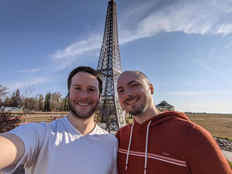 David Walsh, right, and his partner Ivan Slywka, left, in front of the replica Eiffel Tower in Montmartre, Sask. The couple moved in together in Calgary during the COVID-19 lockdown in March 2020. A few months later they moved to Estevan together to start a new life. (Submitted by David Walsh - image credit)