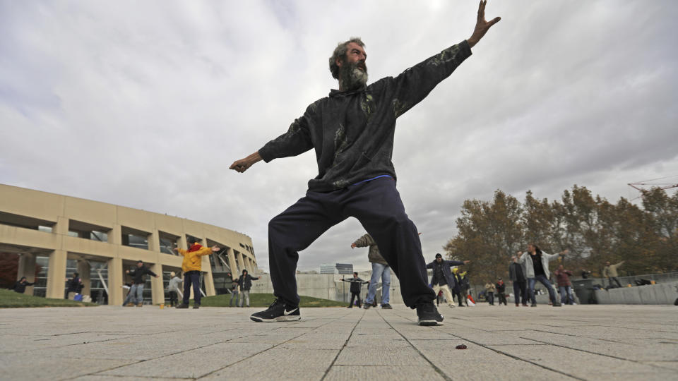 In this Oct. 2, 2019, photo, David Christopher Coons performs tai chi at the Salt Lake City Main Library, in Salt Lake City. The participants are homeless people who take part in a free tai chi program run by a retired couple who started the classes three years earlier. Coons was fired from his job as an electrician about five years ago. He has been homeless since, vacillating between sleeping in shelters or on the streets of Salt Lake City. (AP Photo/Rick Bowmer)