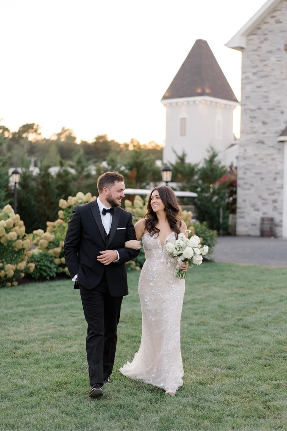 A bride and groom walk together arm in arm.