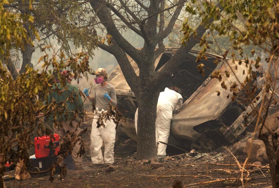 Investigators examine the scene Monday., Aug. 1, 2022 where two victims of the McKinney Fire were found in a vehicle just off Highway 96 near Walker Bridge northwest of Yreka, Calif.