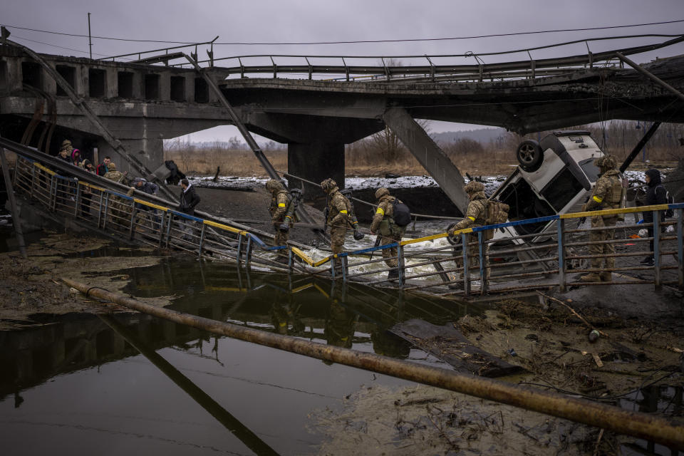 Ukrainian soldiers cross a destroyed bridge, on the outskirts of Kyiv, Ukraine, Wednesday, March 2. 2022. Russia renewed its assault on Ukraine’s second-largest city in a pounding that lit up the skyline with balls of fire over populated areas. That came Wednesday even as both sides said they were ready to resume talks aimed at stopping the new devastating war in Europe. (AP Photo/Emilio Morenatti)