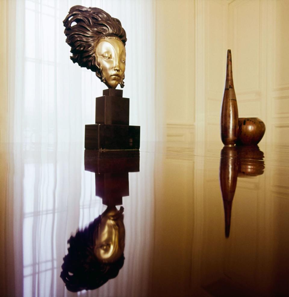 A bronze mask by Alexandre Kelety and two bronze vases by Jean Dunand sit on a lacquered mahogany table also designed by Dunand in Lagerfeld's former Paris apartment, published in Vogue in 1974.